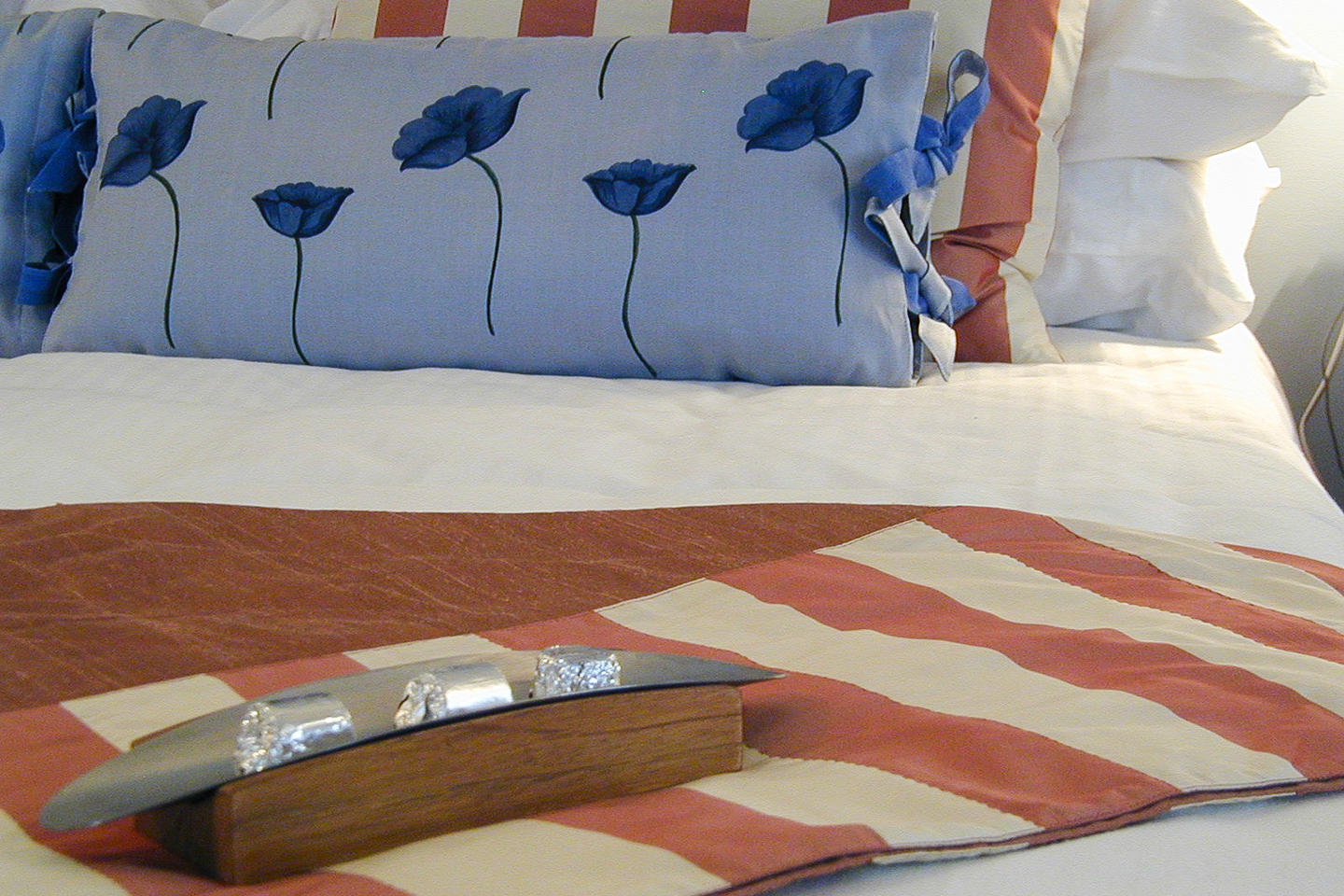 The throw and cushion on the bed in the blue guest room.
