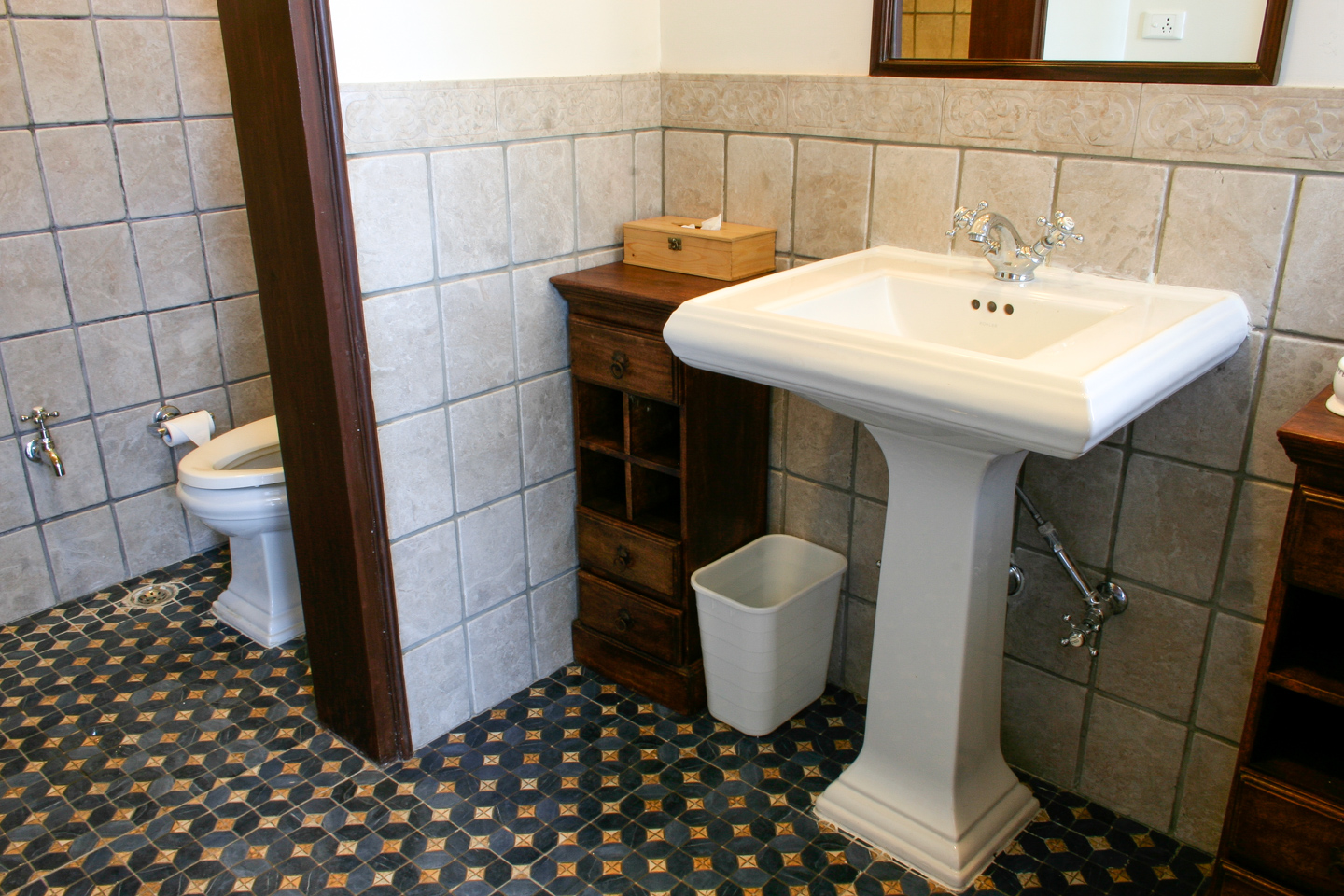 The powder room attached to the conference room is paved with period tiles and has aged stone on the walls.