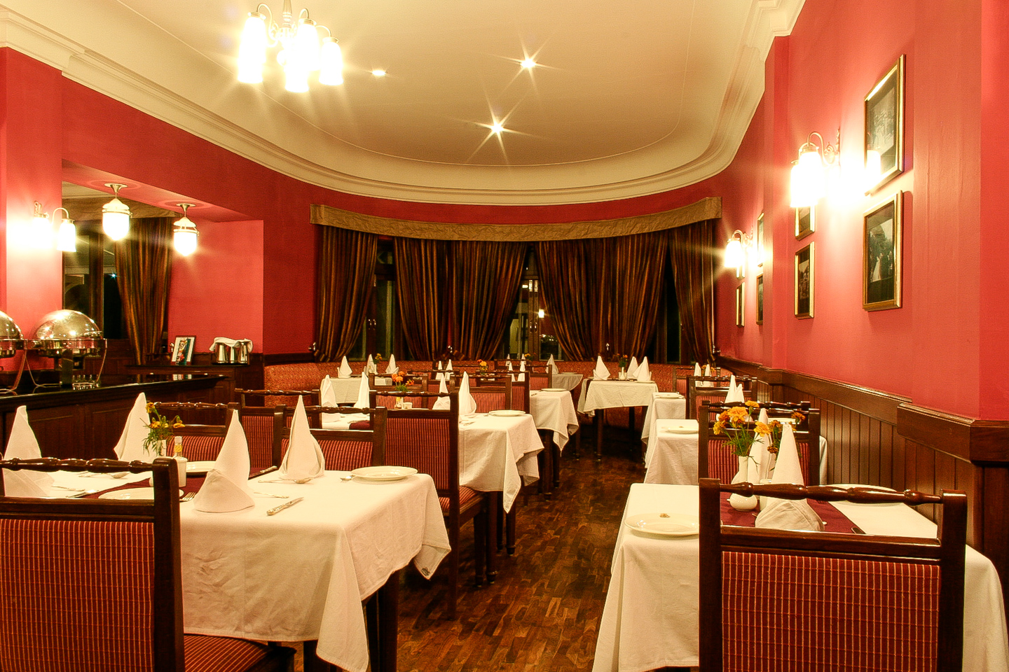 The dining room has wood panelling and deep red walls. The floor is parquet with period tiles.
