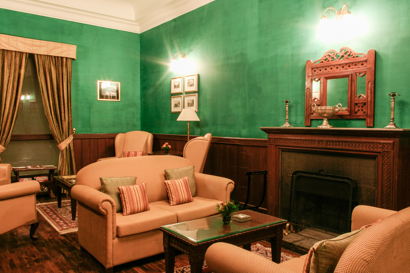 The library has wood panelling and deep green walls. The fireplace is faced in flamed granite and has an intricately carved wooden surround.