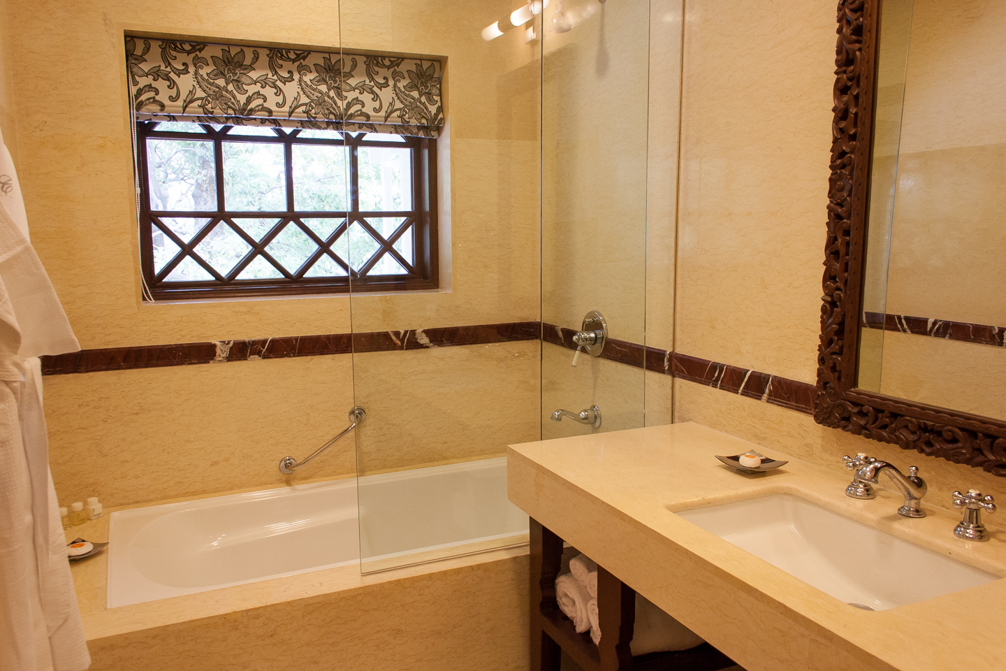 The marble walls are highlighted with trim of carved red marble. The tub has a sliding glass screen.